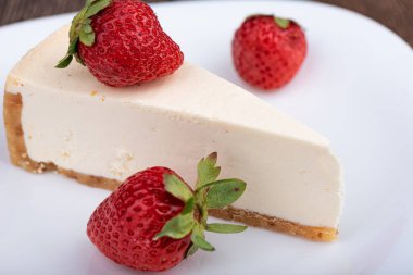 Seçici odaklanma. Beyaz tabakta çilekli cheesecake dilimi. Kapat..