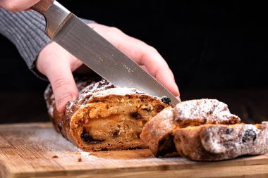 Seçici odaklanma. Kız ev yapımı bir keki bıçakla parçalara ayırıyor. Ahşap arka planda ev yapımı kek..