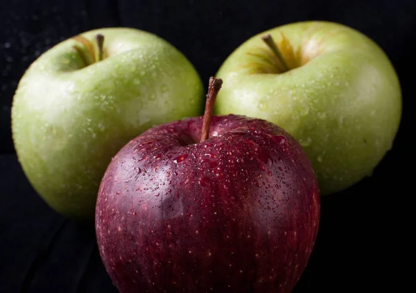 Green and red apples on a black background