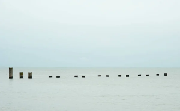 Fifteen concrete piers of the destroyed pier against the horizon