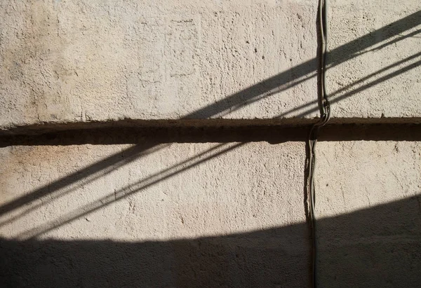 Diagonal shadows on the plastered wall of a building