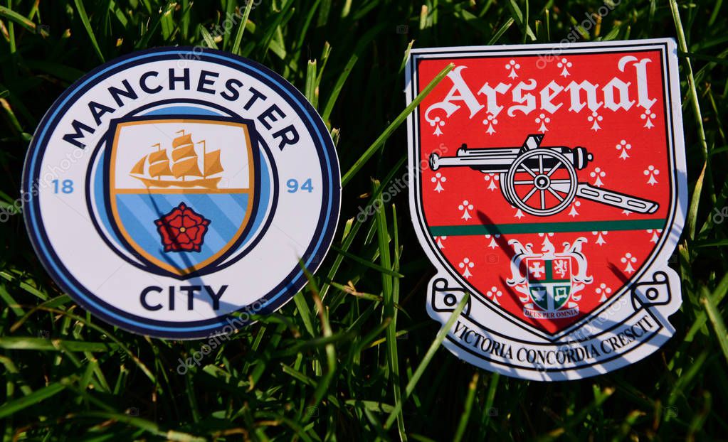 September 6, 2019 London, UK. Emblems of English football clubs Arsenal F.C.  London  and Manchester City on the green lawn grass.