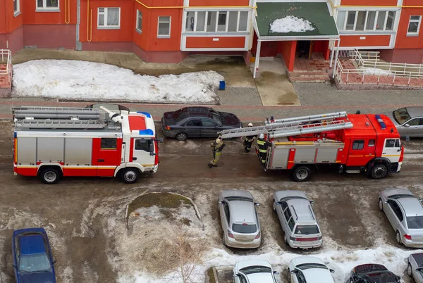 Kışın çok katlı bir konutun bahçesinde itfaiye arabası..