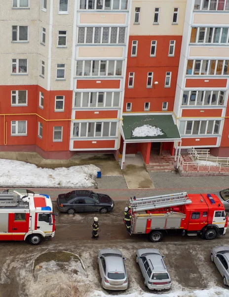 Fire engine in the courtyard of a multi-storey residential building in winter.