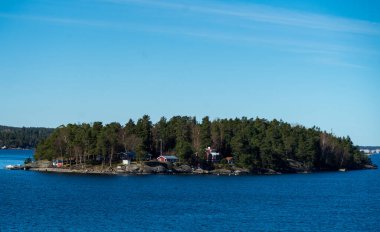 Baltık Denizi 'ndeki Stockholm takımadasının konut adasında geleneksel falun kırmızısına boyanmış resimli yazlıklar..