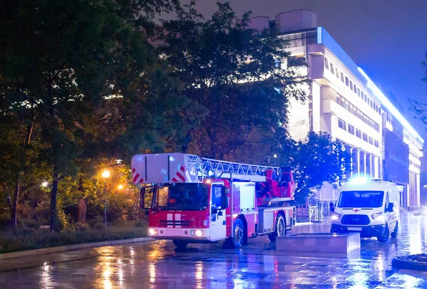 Fire engines in the courtyard of the apartment building where the fire occurred, at night during the rain.