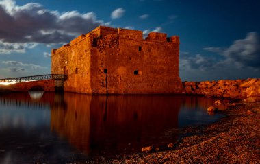 Medieval castle on the shores of the Mediterranean Sea in Paphos city on the island of Cyprus in the light of the full moon. clipart