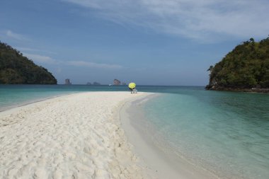 Sahilde şemsiyesi olan dikiz aynalı adam.