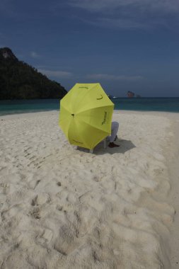 Sahilde şemsiyesi olan dikiz aynalı adam.