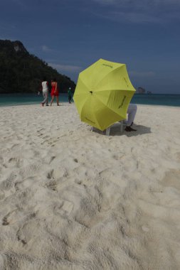 Sahilde şemsiyesi olan dikiz aynalı adam.