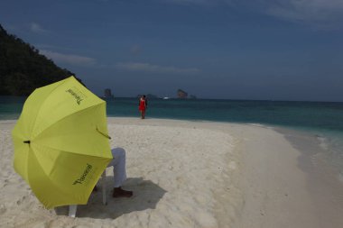 Sahilde şemsiyesi olan dikiz aynalı adam.