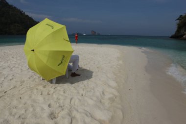 Sahilde şemsiyesi olan dikiz aynalı adam.