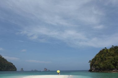 Sahilde şemsiyesi olan dikiz aynalı adam.