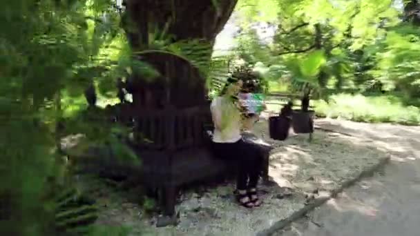 一个女孩附近的一个大而厚的树 在棕榈树 持有一个标志与题词 Ferragosto — 图库视频影像