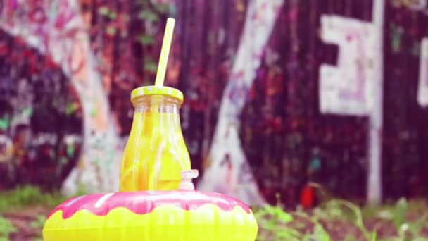 Eine Flasche Orangensaft Einem Aufblasbaren Donut Rotiert Auf Dem Hintergrund — Stockvideo