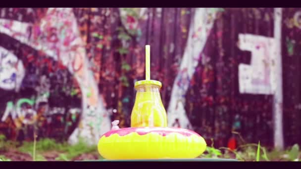 Bottle Orange Juice Inflatable Donut Rotates Background Graffiti — Stock Video