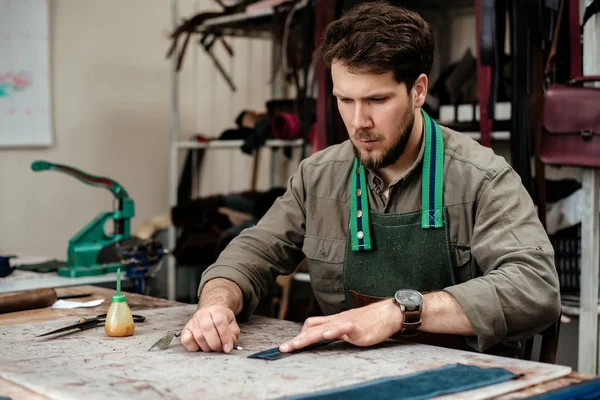 A master works with genuine leather in the workshop Stock Photo