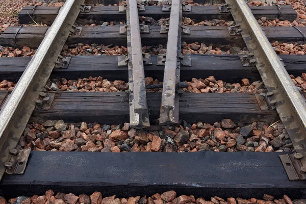 Oiled old steel rails and sleepers on rubble — Stock Photo, Image