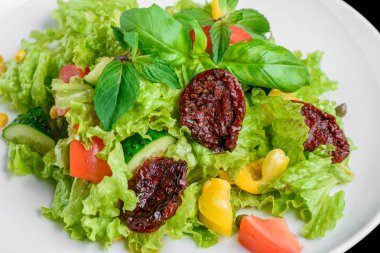 Taze ve kurutulmuş domates, biber, fesleğen izole siyah arka plan üzerine vejetaryen salatası