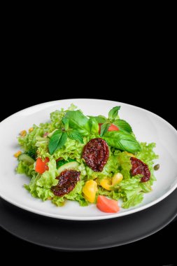 Taze ve kurutulmuş domates, biber, fesleğen izole siyah arka plan üzerine vejetaryen salatası