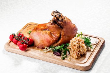 Kızarmış haşlanmış lahana ve domates ahşap kesme tahtası üzerinde kavrulmuş domuz knuckle