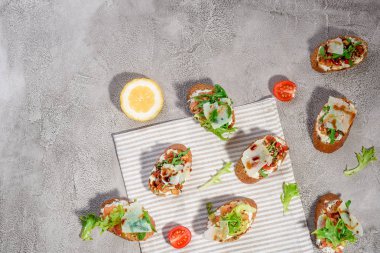 Gri beton veya taş zemin üzerine somon balığı, domates, peynir ve fesleğen pesto ile İtalyan bruschetta.