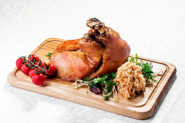 Kızarmış haşlanmış lahana ve domates ahşap kesme tahtası üzerinde kavrulmuş domuz knuckle