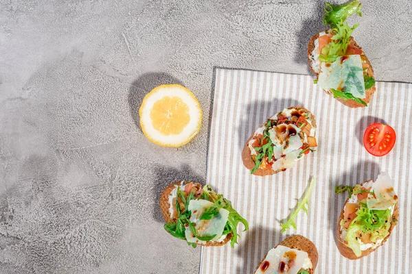 Gri beton veya taş zemin üzerine somon balığı, domates, peynir ve fesleğen pesto ile İtalyan bruschetta.