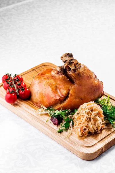 Kızarmış haşlanmış lahana ve domates ahşap kesme tahtası üzerinde kavrulmuş domuz knuckle