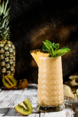 güzel bir cam apineapple ve Kivi Meyve gelen lezzetli smoothies nane hafif ahşap zemin ile dekore edilmiştir. meyve arka plan üzerinde. alanı. yakın çekim