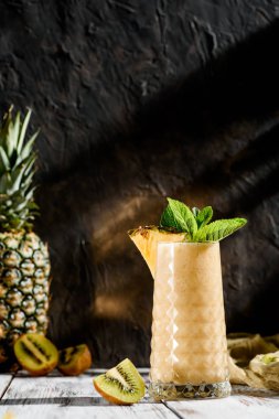 güzel bir cam apineapple ve Kivi Meyve gelen lezzetli smoothies nane hafif ahşap zemin ile dekore edilmiştir. meyve arka plan üzerinde. alanı. yakın çekim