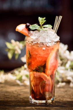 Yaz buzla kokteyl nane ve çiçek bir arka plan üzerinde ahşap bir masa üzerinde meyveleri ile dekore edilmiştir. Berry mojito 