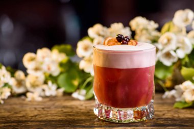 Yaz kokteyl katmanlarında, bir dut ve turuncu bir dilim ile dekore edilmiştir. bir çiçek arka plan üzerinde