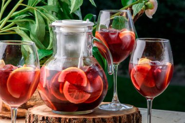 buz ve arka plan yeşil yaprakların üzerinde limon dilimleri ile kırmızı içecek yenileniyor.