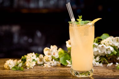 sarı yaz kokteyl çiçek bir arka plan üzerinde ahşap bir masa üzerine nane ve limon kabuğu ile dekore edilmiş