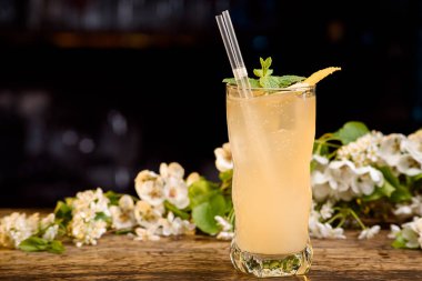 sarı yaz kokteyl çiçek bir arka plan üzerinde ahşap bir masa üzerine nane ve limon kabuğu ile dekore edilmiş