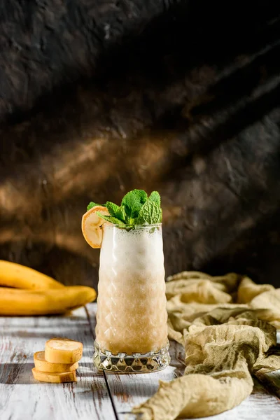 Heerlijke smoothies van een banaan in een mooi glas versierd met mint op een houten achtergrond — Stockfoto