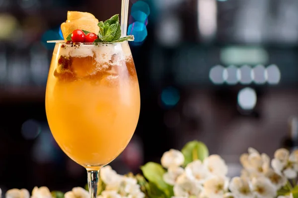 Летний коктейль, украшенный ягодами и мятой на барной стойке на цветочном фоне — стоковое фото