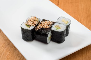 ahşap arka plan üzerinde beyaz tabakta izole avokado ile rulo. yakın çekim