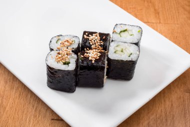 Maki ahşap arka plan üzerinde beyaz tabakta izole salatalık ile. yakın çekim