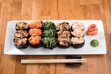 Çiçekler arasında beyaz tabakta somon balığı, yılanbalığı, chukka, karides ve tavuk etli ayarla Gunkan suşi. ahşap bacground. Geleneksel Japon mutfağı. yakın çekim