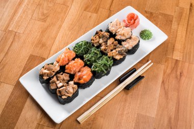 Çiçekler arasında beyaz tabakta somon balığı, yılanbalığı, chukka, karides ve tavuk etli ayarla Gunkan suşi. ahşap bacground. Geleneksel Japon mutfağı. yakın çekim