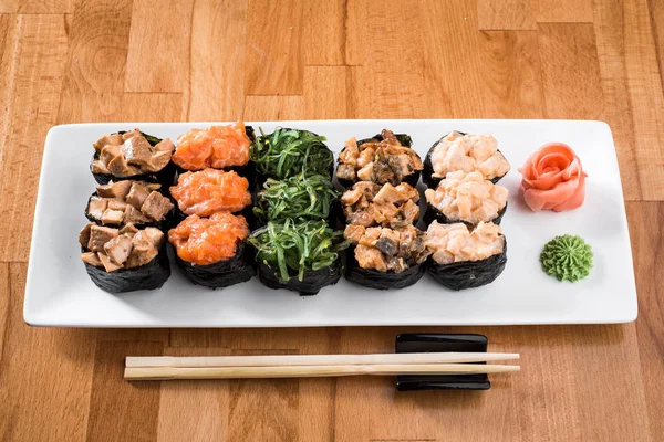 Çiçekler arasında beyaz tabakta somon balığı, yılanbalığı, chukka, karides ve tavuk etli ayarla Gunkan suşi. ahşap bacground. Geleneksel Japon mutfağı. yakın çekim