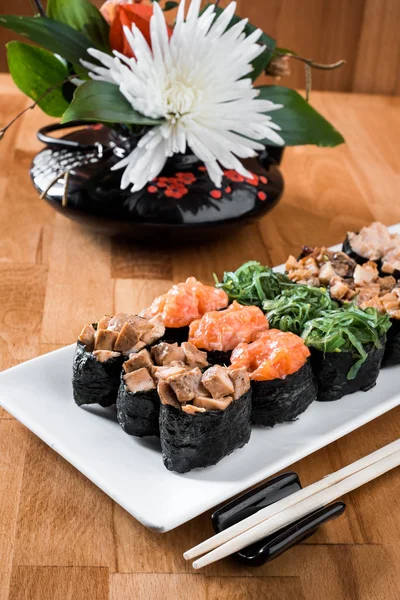 Somon balığı, yılanbalığı, chukka, karides ve tavuk etli beyaz bir tabağa ayarla Gunkan suşi. ahşap bacground. Geleneksel Japon mutfağı. yakın çekim