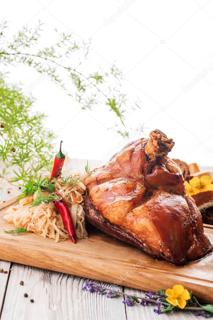 Roasted pork knuckle with braised boiled cabbage and pepper on wooden cutting board. close up. isolated
