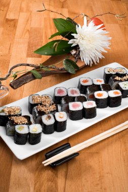  Maki Sushi somon, ton balığı, yılanbalığı ve avokado ile beyaz bir plaka üzerinde rulo. yakın çekim.