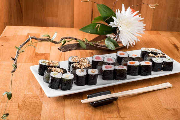 Maki Sushi roule avec du saumon, du thon, de l'anguille et de l'avocat sur une assiette blanche. gros plan . — Photo