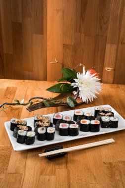  Maki Sushi somon, ton balığı, yılanbalığı ve avokado ile beyaz bir plaka üzerinde rulo. yakın çekim. 