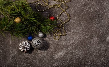 Yılbaşı kartında ağaç dalları, oyuncaklar ve koyu bir arka planda süslemeler var. Yazılar için bir yer var.