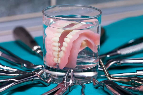 Diş Aletleriyle Çevrili Bir Bardakta Yapay Dişler — Stok fotoğraf